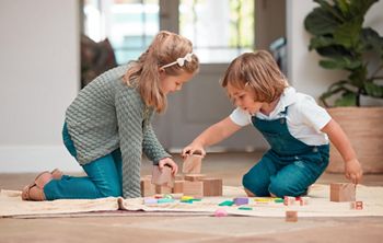 Playing, children and wooden blocks in house, fun and bonding of family, growth and development in lounge. Games, kids and learning with toys, siblings and together in living room, floor and home.