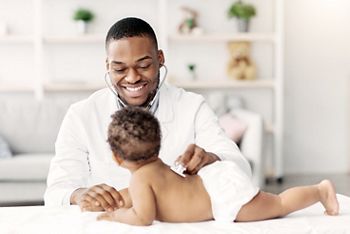 Medical Checkup. Smiling Black Pediatrician Doctor Examining Little Baby With Stethoscope During Appointment In Modern Clinic, Professional Therapist Checking Health Of Infant Child, Free Space