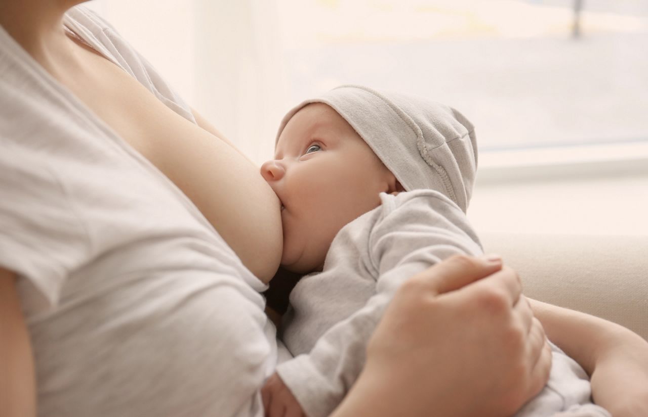Young woman breastfeeding her little baby at home