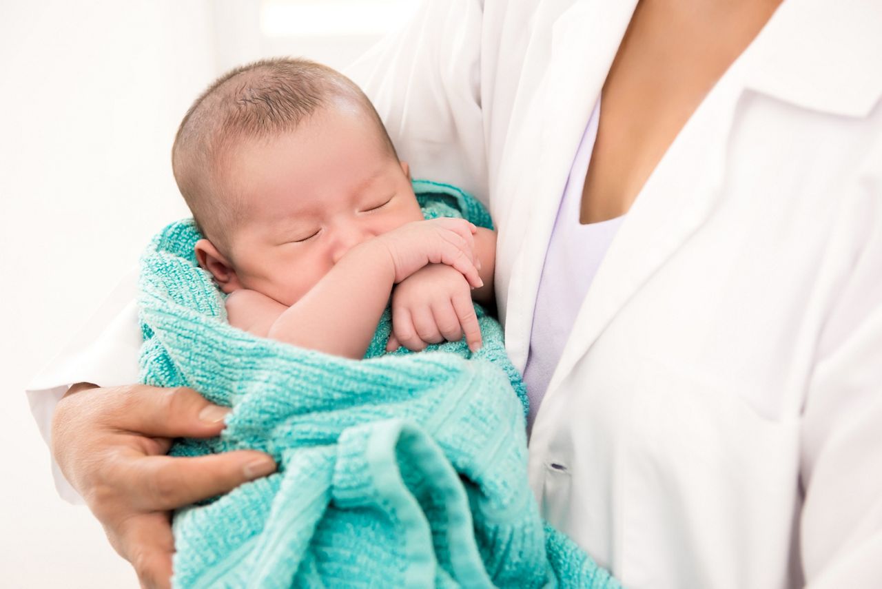 Doctor holding sleeping newborn baby in the arms