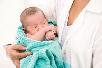 Doctor holding sleeping newborn baby in the arms