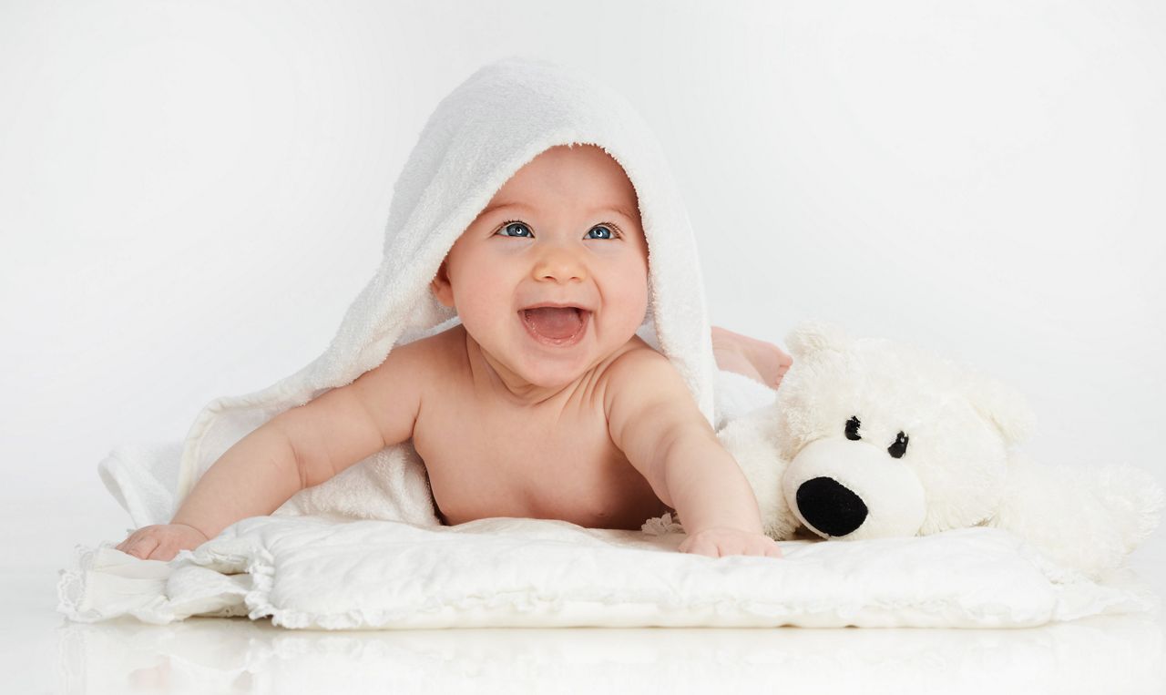 little child baby smiling lying under thr towel