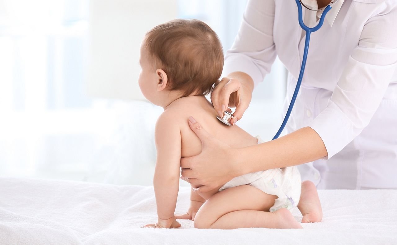 Female doctor examining baby boy in clinic