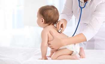 Female doctor examining baby boy in clinic