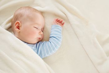 little boy sleeping on soft white blanket