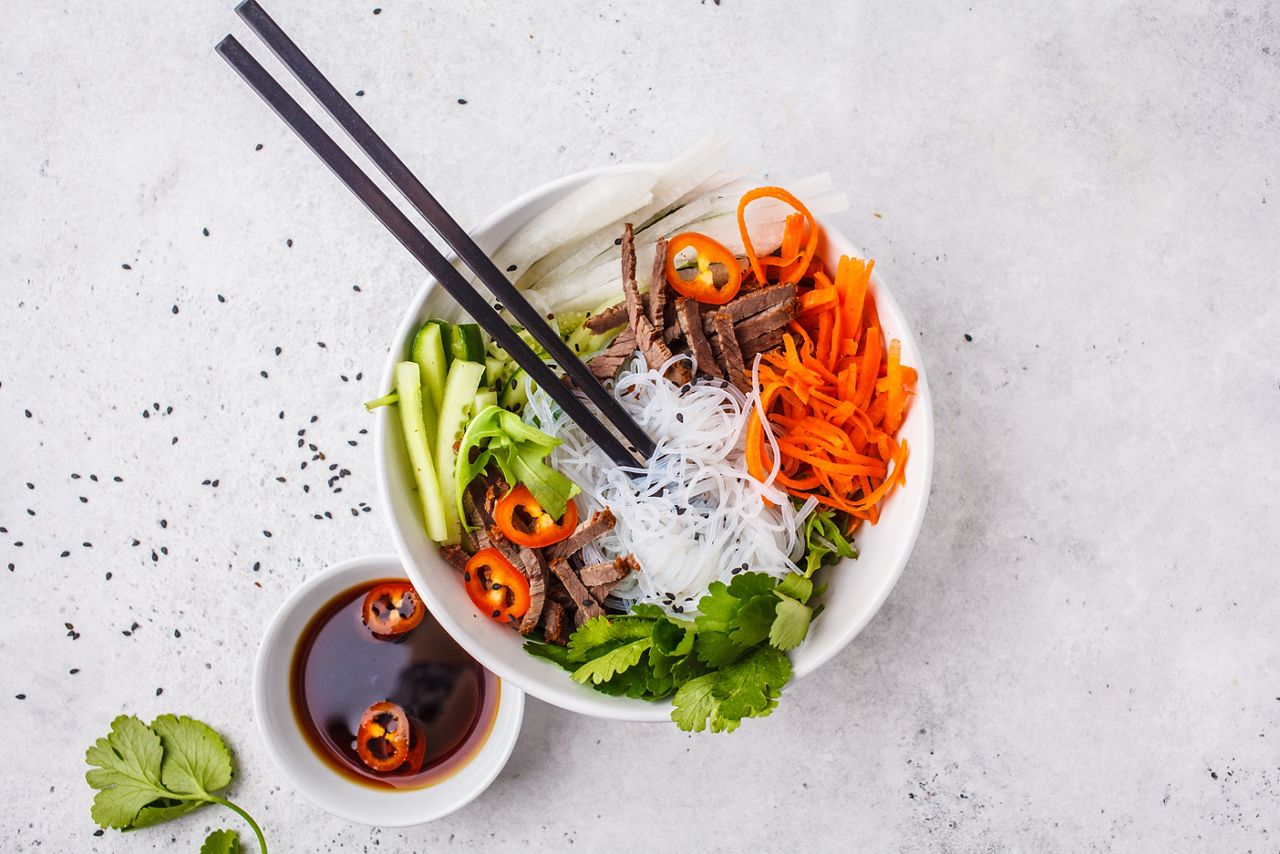 Bun cha salad bowl. Vietnamese rice noodle with beef and chilli vegetables salad in white bowl, top view.