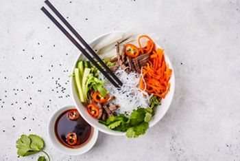 Bun cha salad bowl. Vietnamese rice noodle with beef and chilli vegetables salad in white bowl, top view.