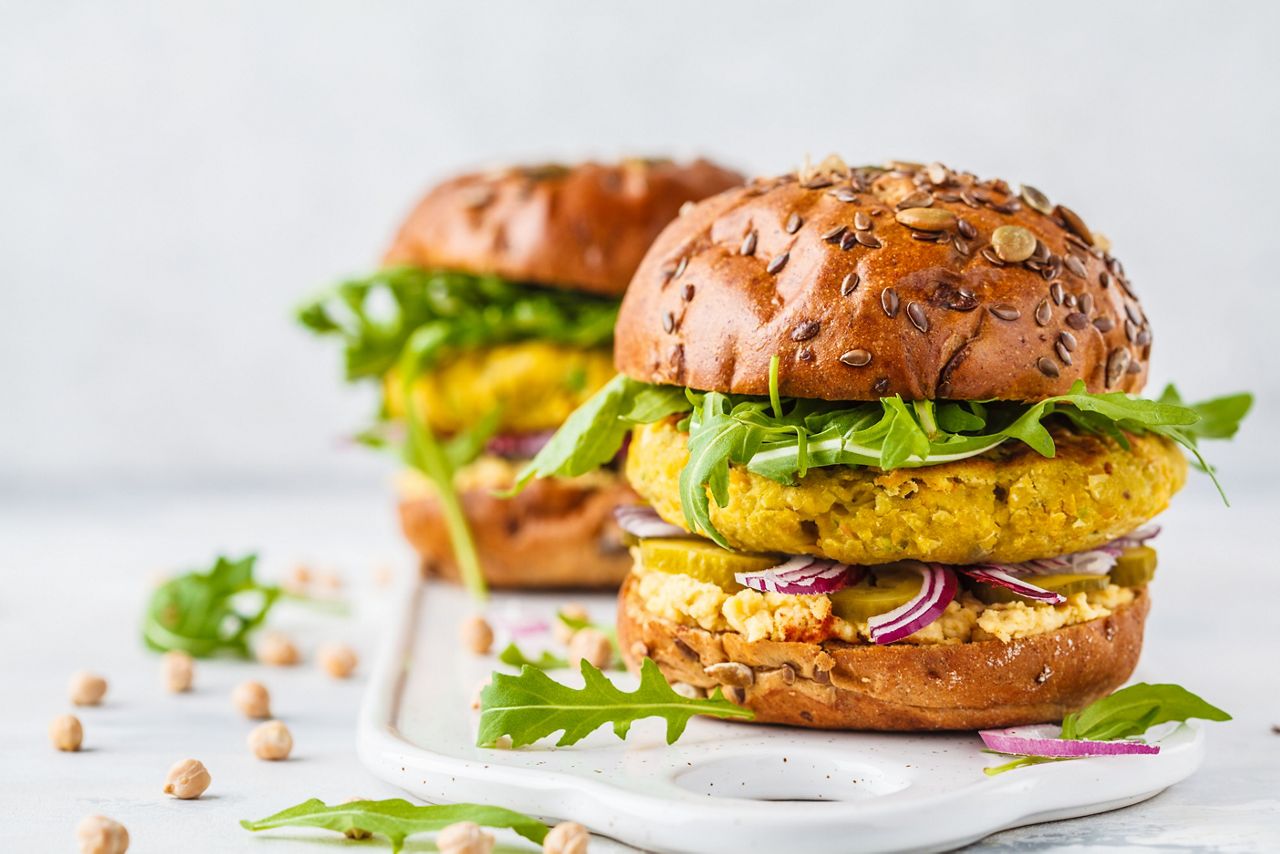 Vegan chickpeas burgers with arugula, pickled cucumbers and hummus. Plant based diet concept.