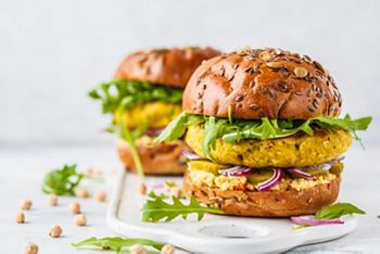 Vegan chickpeas burgers with arugula, pickled cucumbers and hummus. Plant based diet concept.