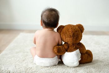 Back of a baby with a teddy bear