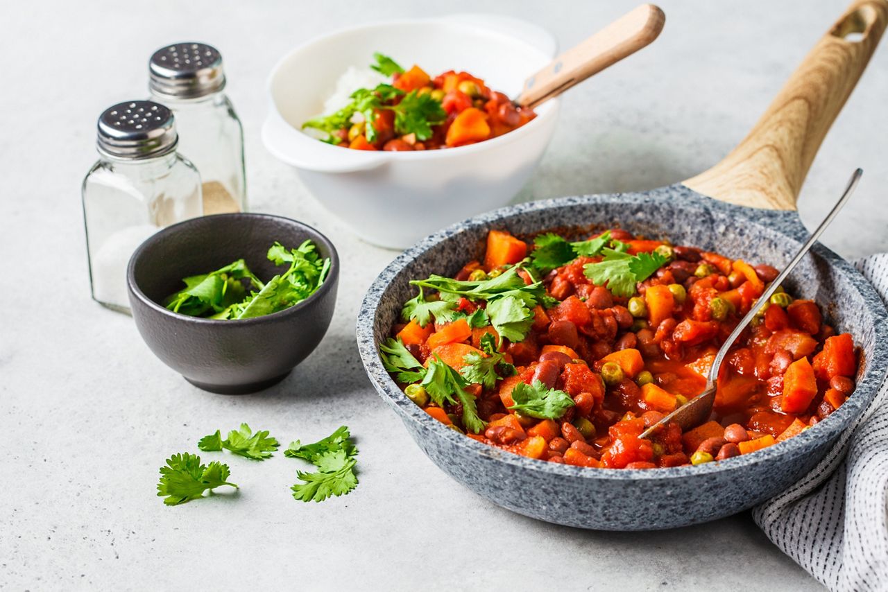 Vegan bean stew with tomatoes and rice in a pan over white background. Vegan food concept.