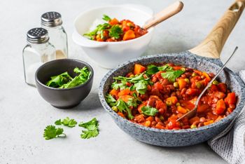 Vegan bean stew with tomatoes and rice in a pan over white background. Vegan food concept.