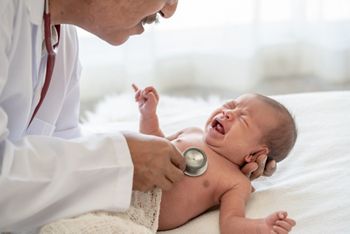 Crying asian newborn baby girl check up examines by pediatrician doctor. Happy male doctor hand using stethoscope examining little cute baby infant heart and lung in clinic. Baby health care concept.