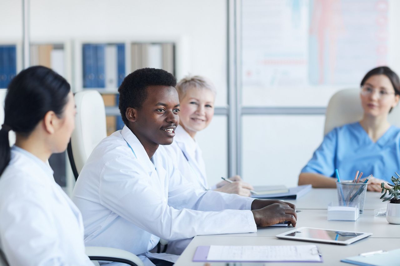 Portrait of young African-American doctor speaking during medical conference and smiling happily, copy space