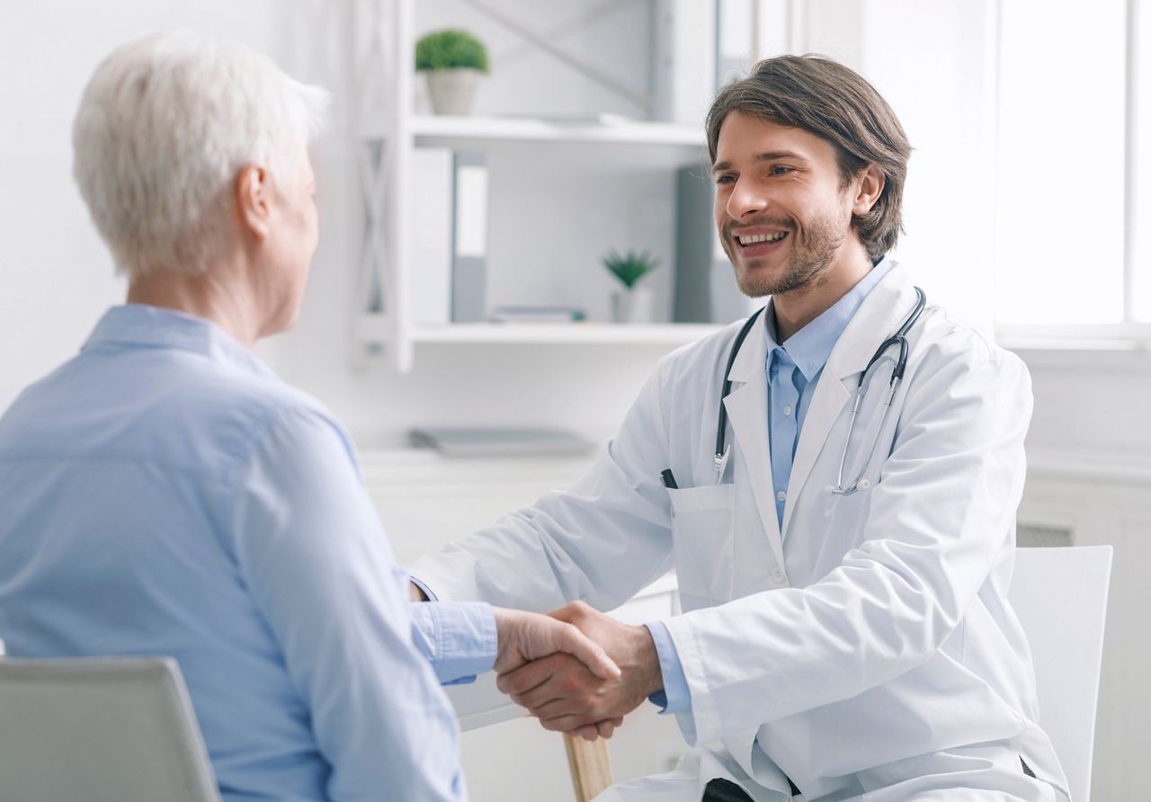 Cheerful general practitioner shaking hands with healthy female patient