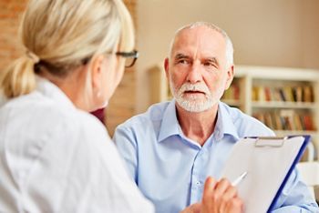 Senior Patient hört seiner Ärztin aufmerksam zu bei Beratung in der Sprechstunde