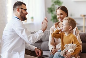 family doctor pediatrician conducts examination of child boy who came with his mother,  and giving high five to him  
