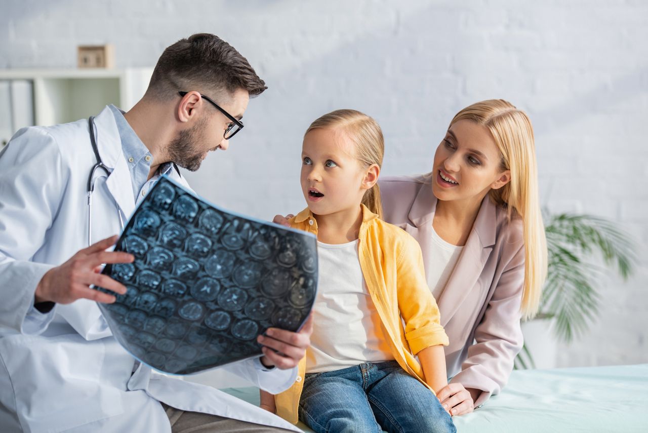 Pediatrician holding blurred mri scan near amazed kid and mother