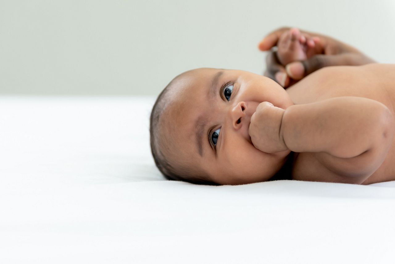 Portrait images of African gril baby newborn is 3-mount-old, lying and smile with happy on white bed, to African child and baby newborn concept.