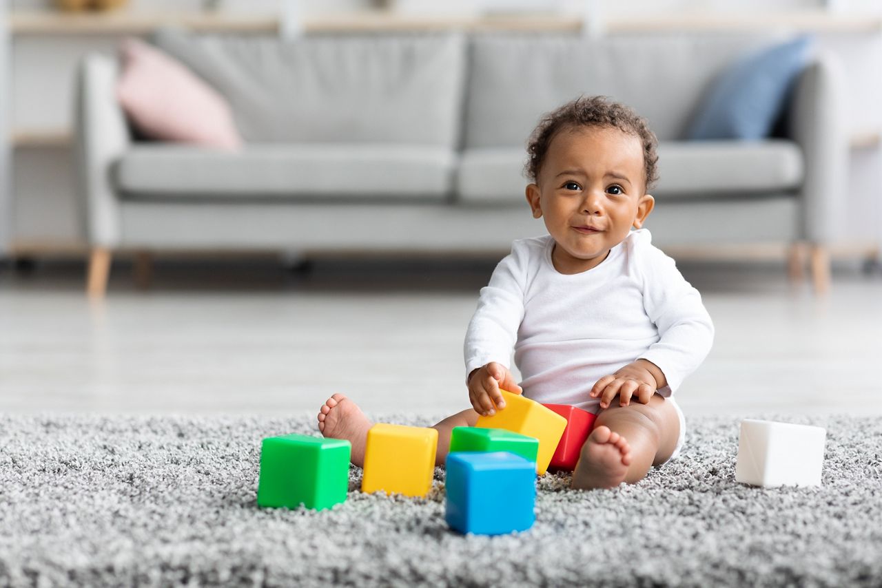Development Games For Babies. Cute African American Infant Child Playing With Stacking Building Blocks At Home, Adorable Little Baby Sitting On Carpet In Living Room And Looking At Camera, Copy Space