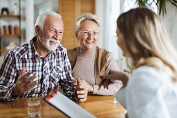 Happy senior couple talking  with their female nurse  at home