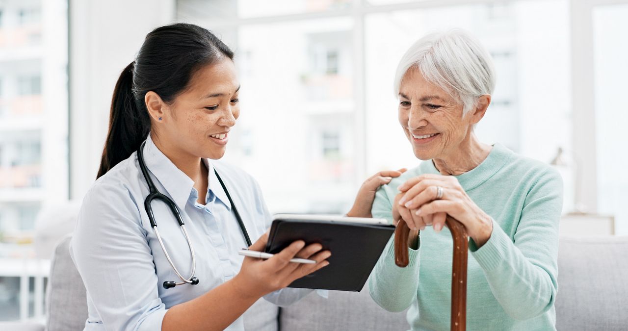 Talking, old woman or doctor with tablet for results, report or report history online in hospital in consultation. Support, healthcare or Asian nurse with medical update for elderly patient in clinic.