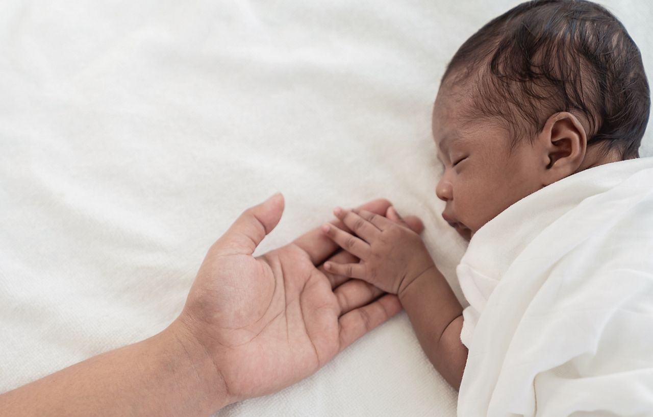 African black parent hands holding newborn baby fingers, Closeup mother’s hand holding their new born baby day. Together love harmony family nursery healthcare and medical father’s day concept banner