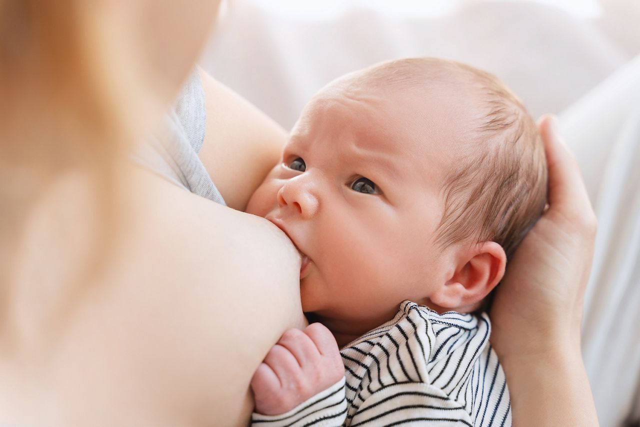 Mother breastfeeding baby. Concept of bonding mother and baby, healthy physical and mental development of child, natural parenting. Baby eating mother's milk. Woman nursing and feeding newborn baby.