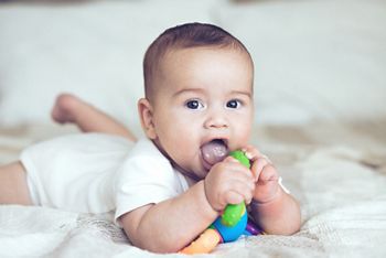 Portrait of a lovable 5 months baby lying down on a blanket and playing with toy
