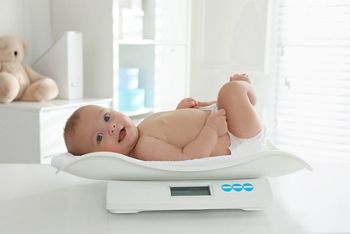 Cute little baby lying on scales in clinic