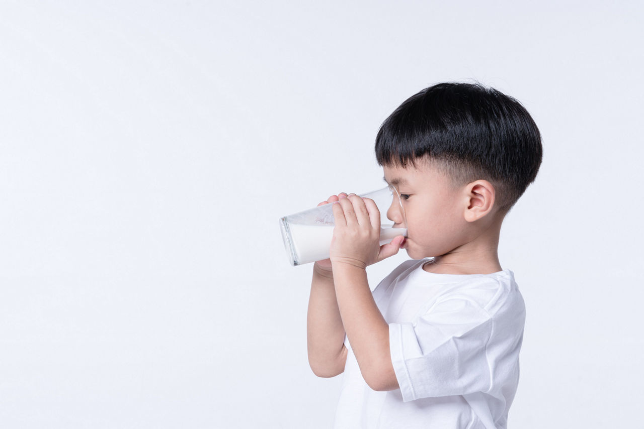 Asian boy about 4 years old drinking milk from glass