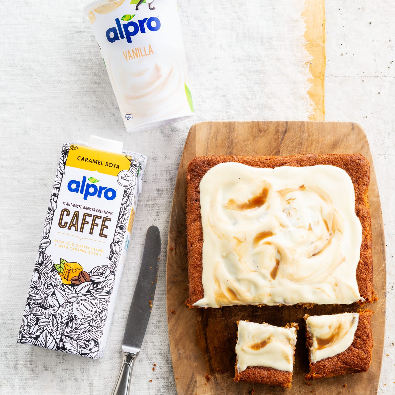5EA28689-5400-48B1-B95C830000DD89DA<br>A_GFY_NA_Master_Recipe_Image_CoffeeTrayBake_1x1__Drinks_NA_Soy_Caramel_TetraUHT_1l_HR_095.tif<br>Frosted Coffee Cake 
Have your coffee and eat it, with this cake made with Alpro Caffè Soya Caramel Drink + Alpro Vanilla plant-based alternative to yogurt
"The bake:
200g soft margarine
150g dark brown sugar
200g self-raising flour
2 tsp baking powder
3 eggs
120g raw parsnips, carrots or sweet potato, grated
100ml Alpro caffe drink Soya Caramel (Or if none to hand, mix 100ml Alpro Vanilla® plant-based alternative to yogurt with 1 tbsp coffee granules & 2 tsp boiling water)
Topping:
200ml Alpro Vanilla alternative to yogurt
10ml Alpro Caffe drink Soya caramel drink (Or ½ tsp coffee granules & 1 tsp boiling water)"
"1. The prep. Pre-heat the oven to 190º/170º fan/gas 5, and line a 28 x18cm ovenproof dish or tray with baking parchment.
2. Get mixing. In a medium-sized bowl whisk together the margarine, sugar, flour, baking powder and eggs for a good three minutes until you have a light, smooth batter, then fold in the grated veg and add the Alpro Caffe drink.
3. Pour into your dish and smooth over the top with a wet spoon, then bake for 35 minutes. When it’s done, let it cool on a wire rack before you add...
4. …the topping. Spread the cake with the Alpro Vanilla alternative to yogurt and drizzle a little of the Alpro caffe drink or your coffee mixture over the top. Now here’s the clever bit. Using the end of a spoon, drag it gently over the surface to produce coffee-coloured swirls. Be as creative as you like! Delish as an after-dinner dessert or a daytime treat."
lactose free, veggie
/coffee-traybake
(Recipe type: Desserts/BAKING/SNACKS (Prep time: 15 min) (cooking time: 25 min) (baking time: 35 min) (cooling time: 20 min) (servings: +/- 12 persons) (season: autumn) (pool: 1) NOT TO BE TRANSLATED
/
/
/
/
Alpro Caffè Soya Caramel Drink + Alpro Vanilla plant-based alternative to yogurt
Alpro, Alpro recipe, desserts, cake, pie, carrot cake, snacks