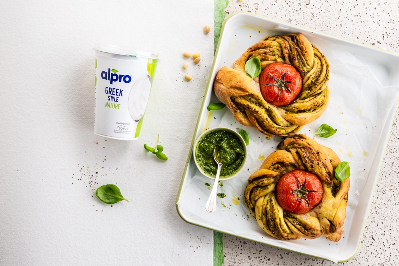 88137759-6818-4511-B9B34C67FC41B9A5<br>A_GFY_NA_Master_Recipe_Image_Flatbread__PBAQ_NA_Soy_NA_NA_500g__ HR_withpack_horizontal.tif<br>Braided flatbread with roasted tomato. 
A brilliant brunchtime savoury bake made with Alpro Greek Style. 
Ingredients: 
1 tsp sugar
125ml lukewarm water
7g dried yeast
500ml flour 
125g Alpro Greek Style
1 tsp salt
1 garlic clove, finely grated 
Olive oil
4 tbsp green pesto (plus extra for serving if you like)
4 medium tomatoes (with stems if you can)
Salt & pepper to taste

1. Preheat your oven to 180º. Then activate the yeast. In a small bowl, mix together the sugar, warm water and yeast. Leave for around 10 minutes – when it looks foamy, the yeast is activated and it’s ready to use. 
2. Now for the dough. On a flat surface, make a little heap of the flour. Make a well in the middle and add the yeast mixture, Alpro Greek Style, salt, garlic and a drizzle of oil. Bring it all together and knead the dough for about 10 minutes until it’s sticky and glossy. Pop into a bowl, cover with a damp cloth and leave it for around an hour in a warm place to rise – it should be double the size. (In a gently warmed oven or near a heater is ideal.) 
3. Create your plaits. Divide the dough into 4 pieces. On a floured surface shape each one into a ball then roll out into a round ""pizza"" shape, about 20cm across. Spread a tablespoon of pesto evenly over each round then roll it up tightly. With a sharp knife slice lengthwise down the middle of each ‘sausage’. Braid the two sections together, trying to keep the cut side on top. (That’s what creates the fanatastic twisted effect.) 
3. Arrange the tomatoes on a baking tray lined with baking paper, spacing out well. Wrap a dough plait around each tomato and pinch the ends together to form a wreath. Drizzle with olive oil, season with salt and pepper. 
4. Pop in the oven and bake for 20-25 minutes until the bread is light golden brown. Use a slice to slide onto plates, serve warm with a little extra pesto on the side if you like. Lunch, brunch, delish whenever!