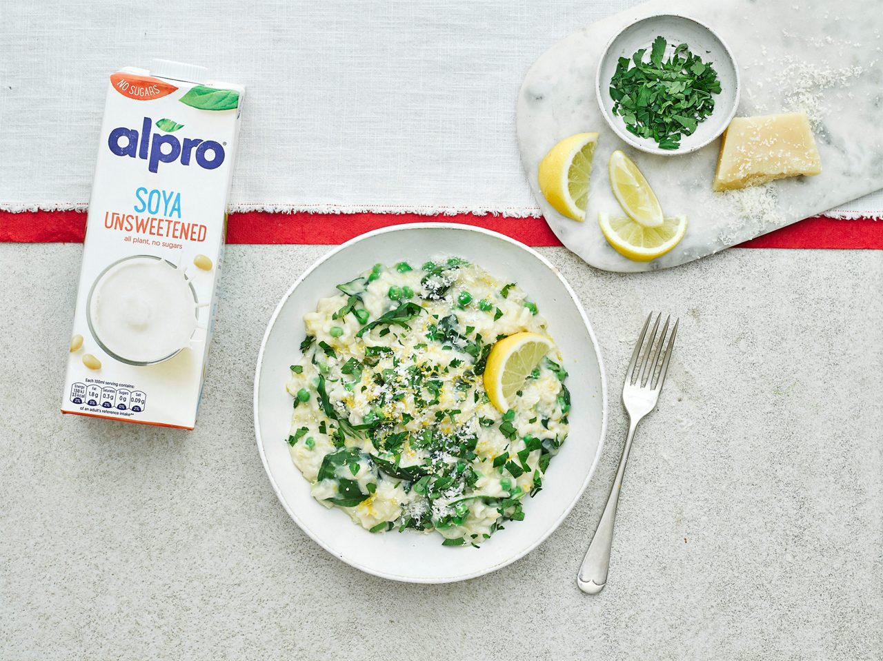 74DC1072-D225-4A5A-BBD0835634004DAF<br>R+T-Alpro_UnsweetenedRecipes-Risotto_02601.jpg<br>Serves: 4-6
Total time: 50 minutes

Ingredients: 
Olive oil, for frying
1 onion, finely chopped
2 leeks, finely sliced
300g Arborio rice
500ml Alpro Soya Unsweetened drink
700ml vegetable stock
1 lemon, juice and zest, plus extra wedges to serve
100g spinach
200g peas
50g Parmesan, optional, plus extra to serve (or use vegan Parmesan) 
Flat leaf parsley, chopped to serve

Method:
1.	Put the stock into a medium saucepan and gently warm through, keep on a low heat until ready to use. In a large deep casserole, heat a glug of oil over a medium heat and add the onion and leeks. Gently fry for 10 minutes until soft and starting to turn translucent, season with salt and pepper. Add the rice and stir-fry for 2-3 minutes until the rice starts to turn clear. 

2.	Turn the heat up and start slowly stirring in a ladle of stock at a time. Stirring with a wooden spoon constantly and letting the stock absorb into the rice. Once the stock has been added, slowly add the Alpro Soya Unsweetened drink. Keep cooking on a medium heat, stirring regularly until the rice is almost tender. 

3.	Stir in the lemon juice, spinach and peas and season to taste. If using Parmesan, stir in the cheese now and garnish with the parsley, extra lemon wedges and Parmesan.