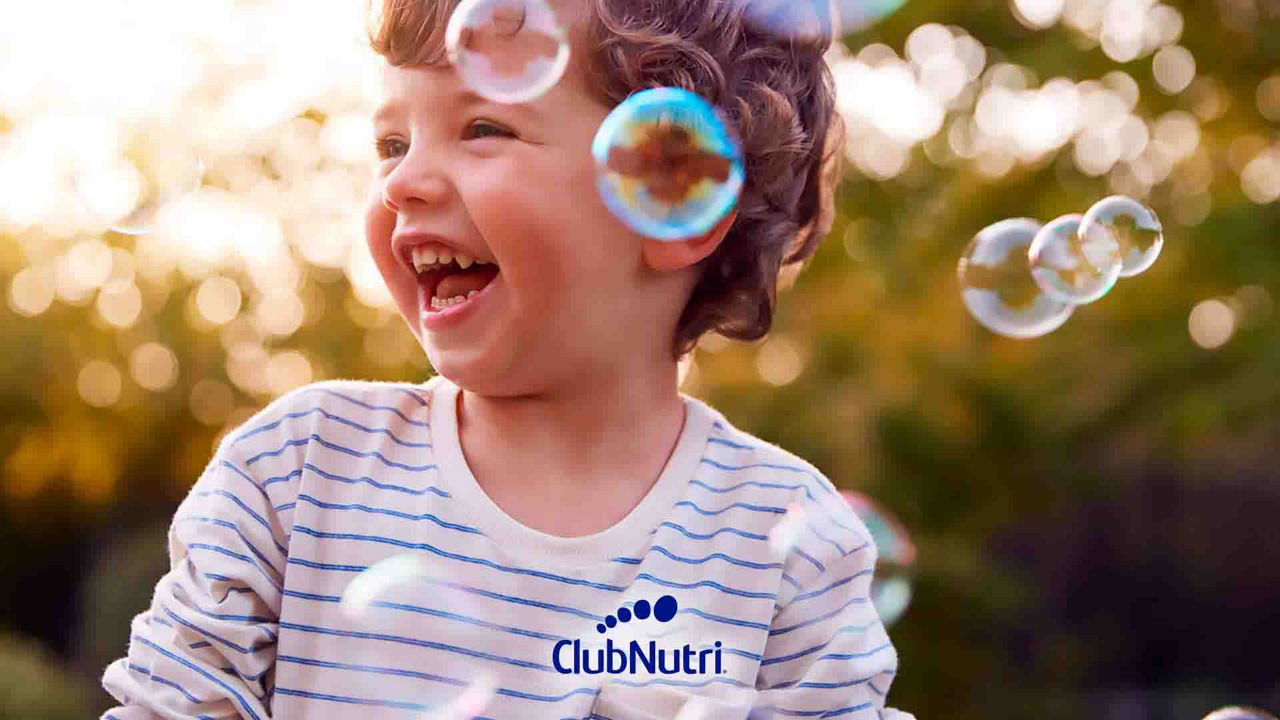 Niño disfrutando y riéndose al aire libre mientras juega con burbujas