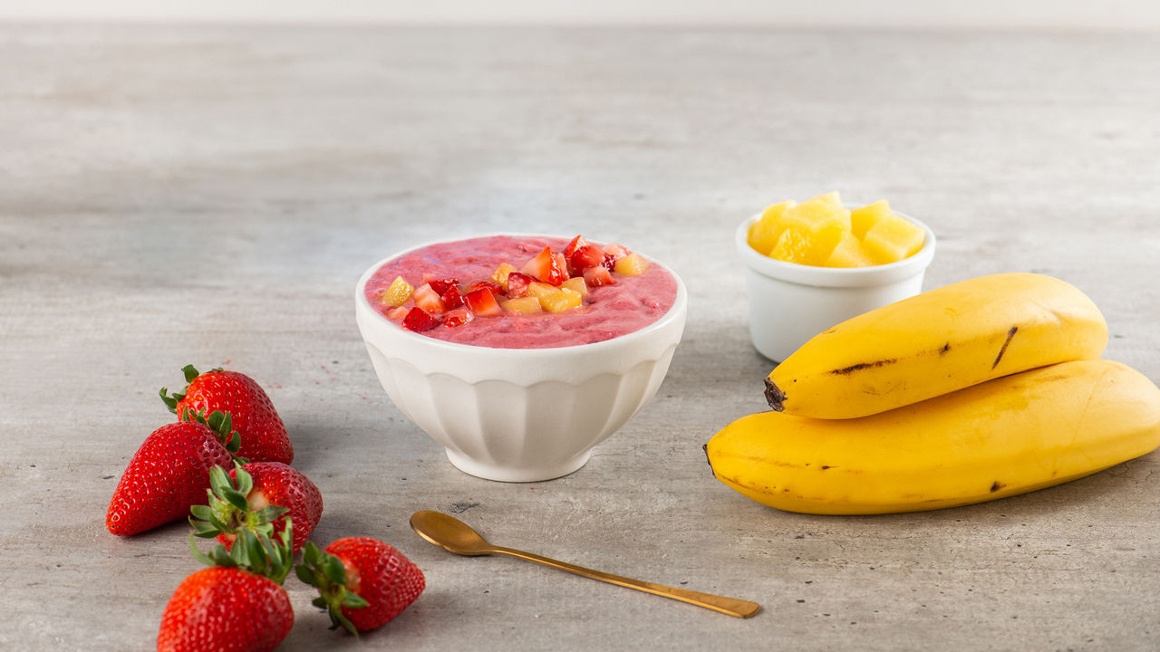 Un tazón lleno de un batido cremoso de frutas hecho con plátanos y fresas, ofreciendo una opción nutritiva y sabrosa