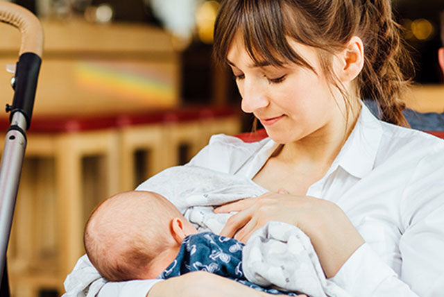 Madre joven amamantando a su bebé en un entorno tranquilo, destacando los beneficios de la lactancia materna para la nutrición y el bienestar del bebé