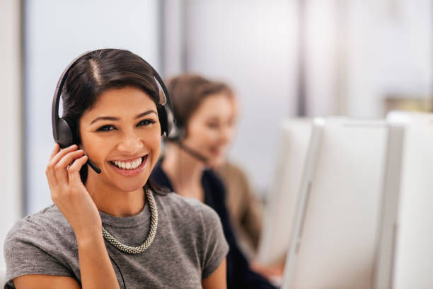Portrait of a call centre agent working in an office with her colleagues in the background
