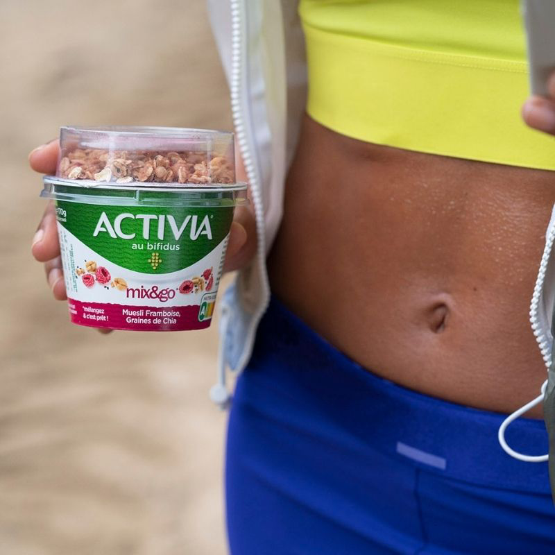 femme qui tient un pot de yaourt dans sa main