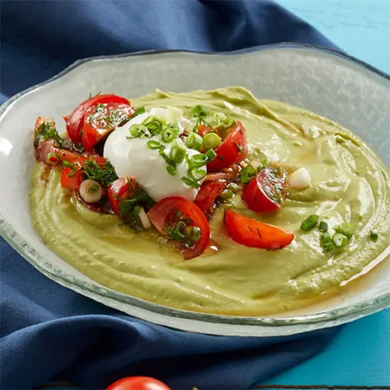 Fresh guacamole with toppings in glass bowl