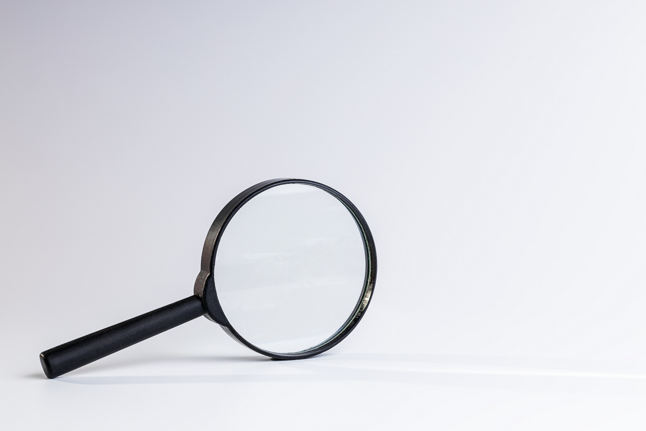 magnifying glass over light grey background. copy space. studio shot. search and marketing concept. minimal.