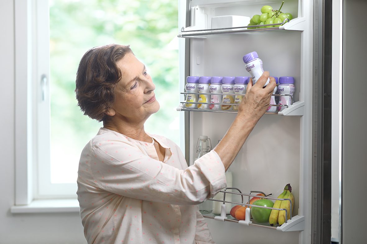 Frau nimmt Fortimel Trinknahrung aus dem Kühlschrank