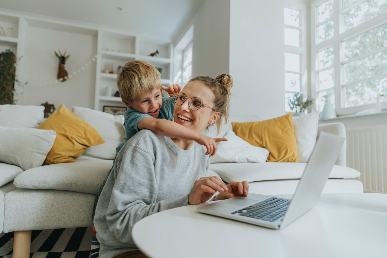 Mother and child using a laptop together in their living room at home, Viersen, NRW, Germany