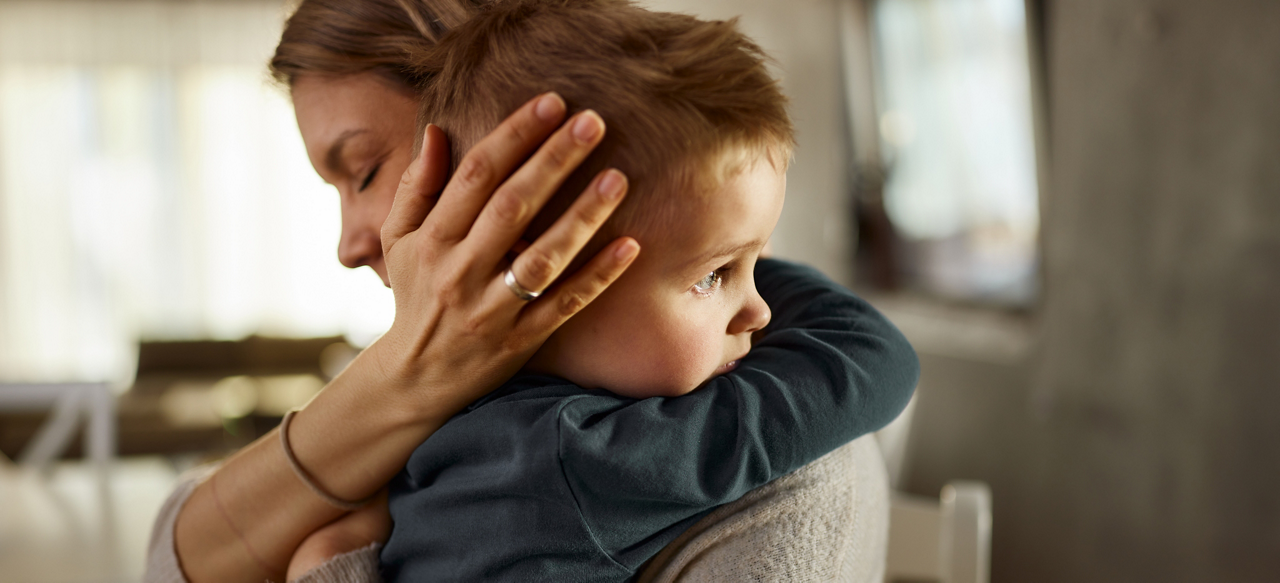 Single mother consoling her sad little boy at home.