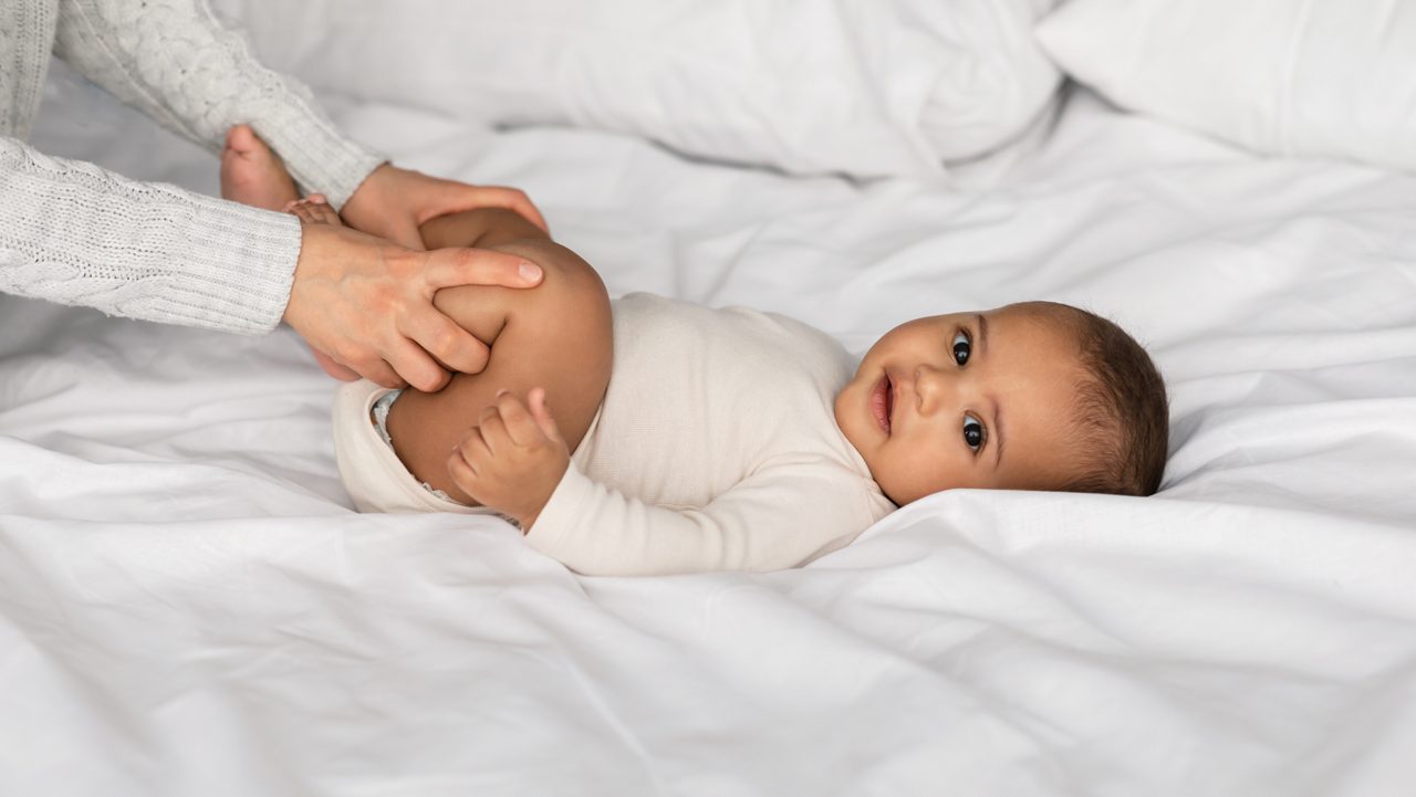 Mutter streckt Beinchen ihres Baby, das unter Verdauungsbeschwerden leidet