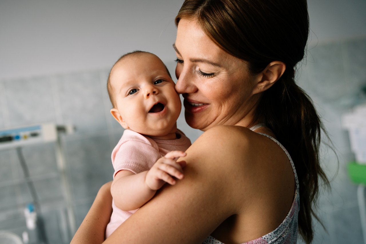 Säugling auf dem Arm der Mutter und Mutter lächeln