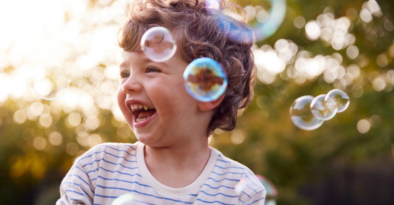 Kleinkind im Garten lacht über Seifenblasen