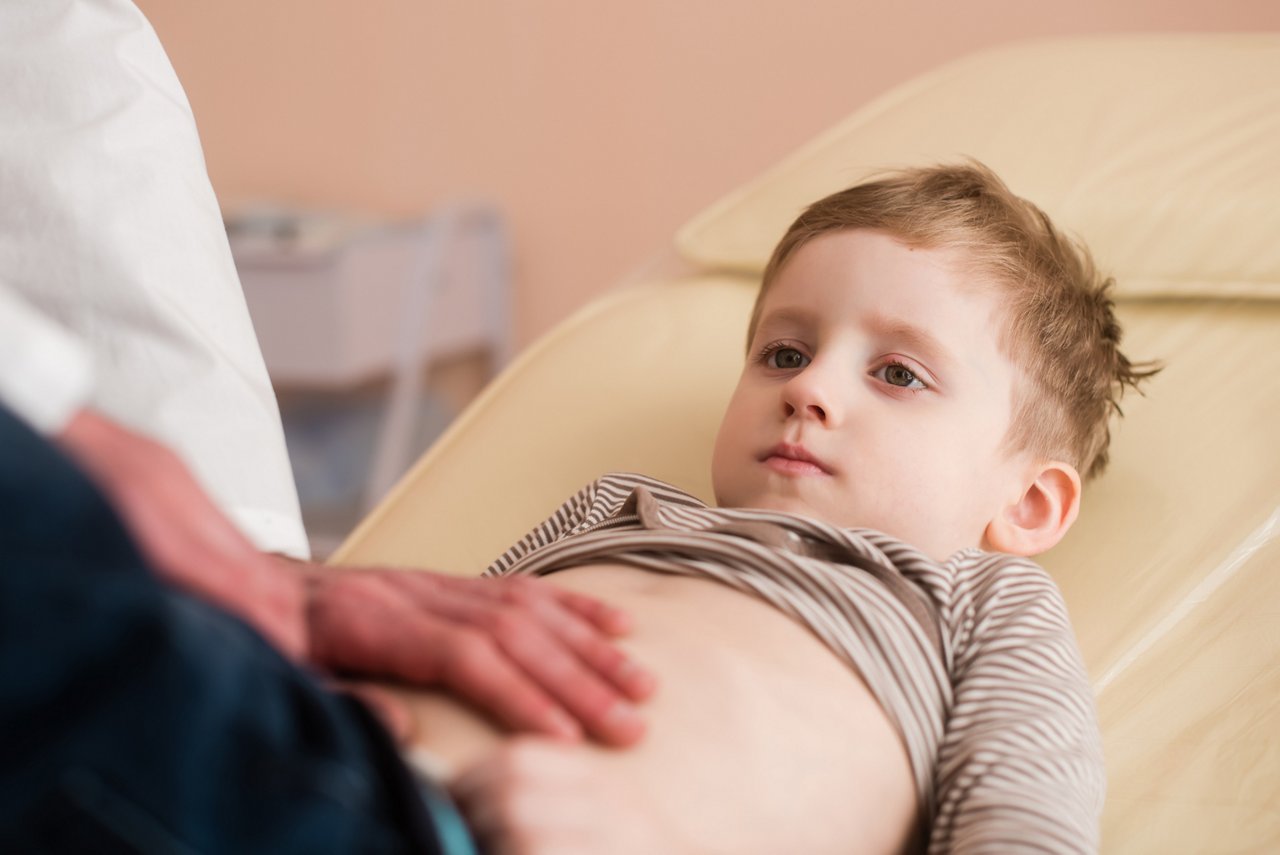 Junge mit EGIE wird vom Arzt am Bauch abgetastet.