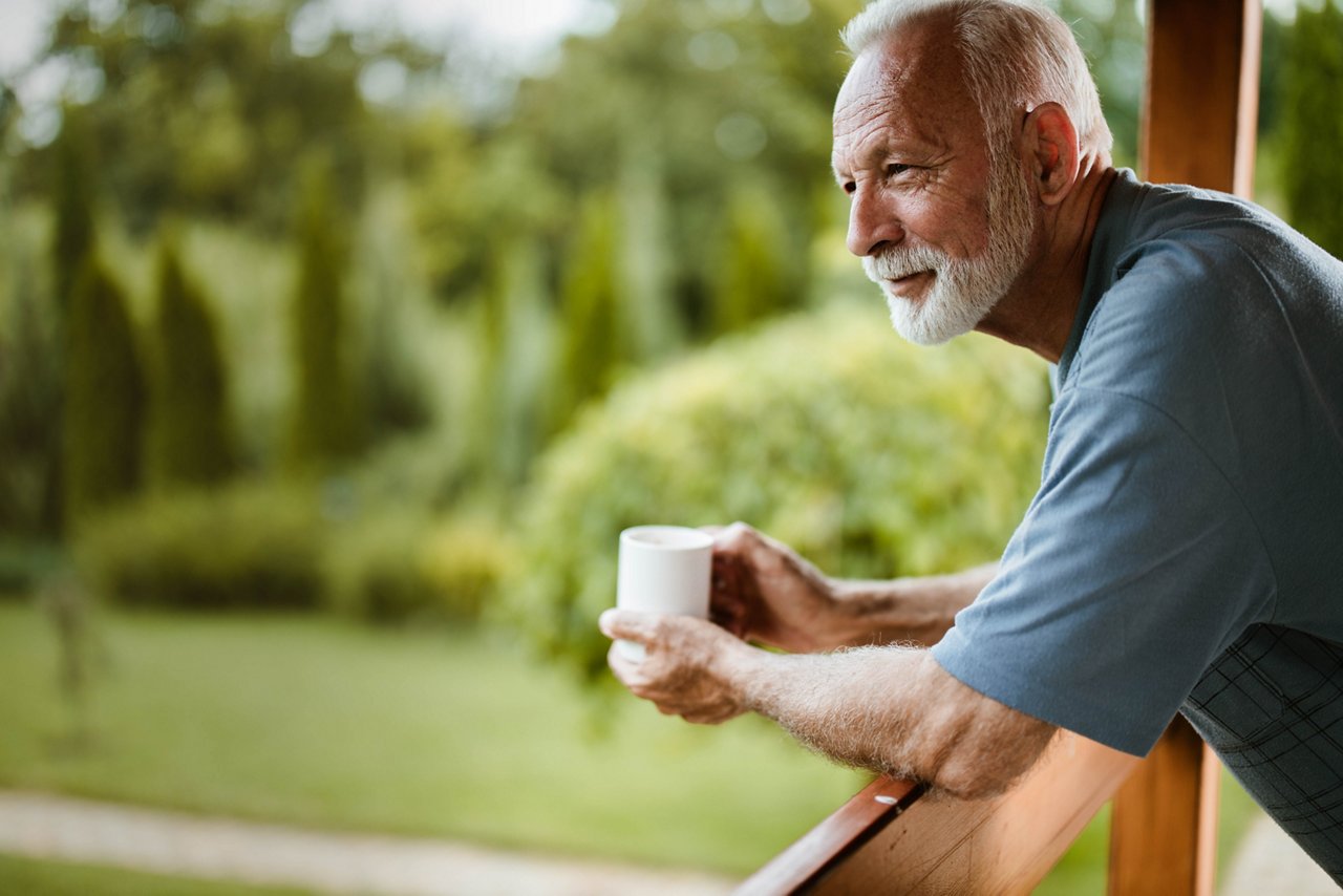 Dysphagie-Patient steht auf Veranda und trinkt zufrieden einen Kaffee