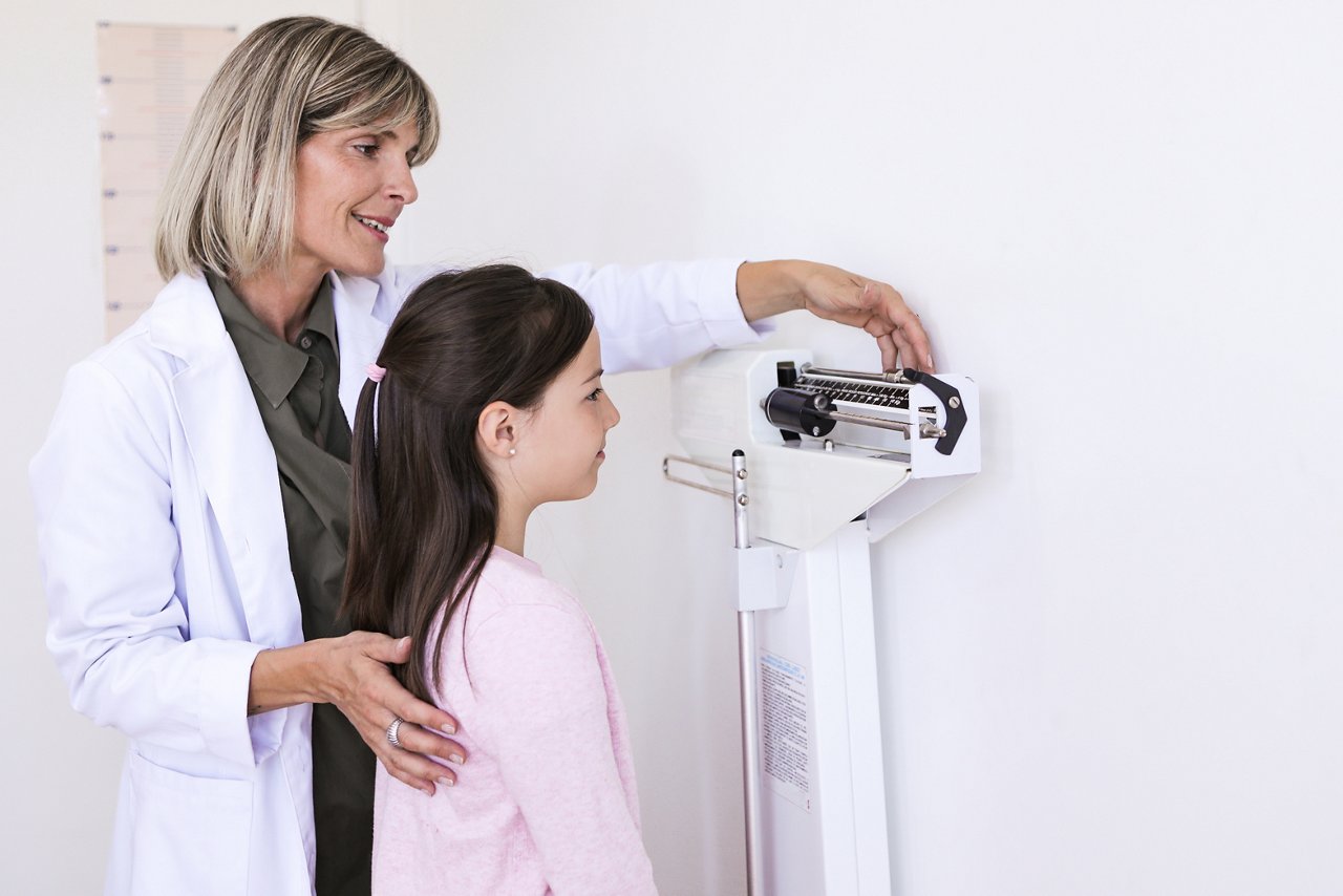 Argentinean nutritionist woman mesuring height and weight of a 9 years-old boy at a balance in the medical office during a medical control- Buenos Aires - Argentina